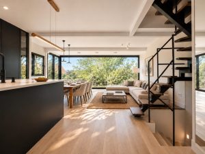 Salón abierto a la cocina negra con escalera volada – reforma integral de chalet en Los Peñascales, Torrelodones