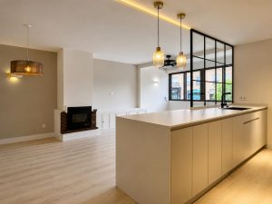 Salón con cerramiento de acero y vidrio hacia la cocina – reforma integral de vivienda en Torrelodones