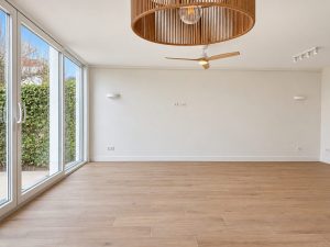 Salón luminoso con lámpara de techo de madera y ventilador, reforma en Alcobendas