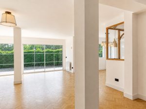 Salón con suelo de roble en espiga y ventanales al jardín · reforma integral en Torrelodones