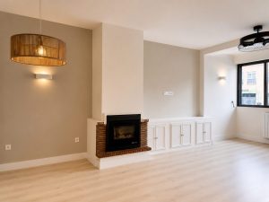 Salón con cerramiento de acero y vidrio hacia la cocina – reforma integral de vivienda en Torrelodones