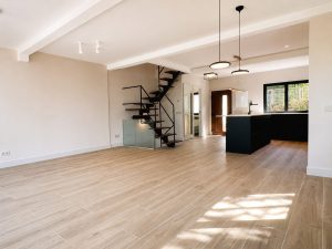 Salón abierto a la cocina negra con escalera volada – reforma integral de chalet en Los Peñascales, Torrelodones