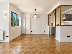 Salón con suelo de roble en espiga y ventanales al jardín · reforma integral en Torrelodones