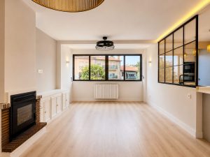 Salón con cerramiento de acero y vidrio hacia la cocina – reforma integral de vivienda en Torrelodones