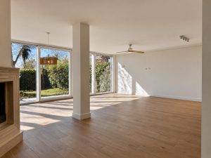 Salón con chimenea y ventanales al jardín tras la reforma, Alcobendas