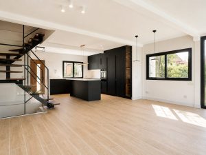 Salón abierto a la cocina negra con escalera volada – reforma integral de chalet en Los Peñascales, Torrelodones