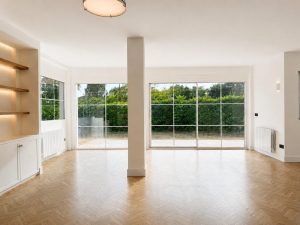 Salón con suelo de roble en espiga y ventanales al jardín · reforma integral en Torrelodones