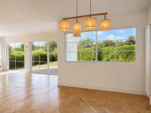 Salón con suelo de roble en espiga y ventanales al jardín · reforma integral en Torrelodones