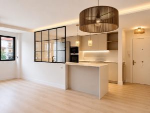 Salón con cerramiento de acero y vidrio hacia la cocina – reforma integral de vivienda en Torrelodones