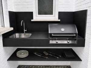 Cocina exterior con barbacoa y encimera negra – reforma de terraza y patio en Pozuelo de Alarcón