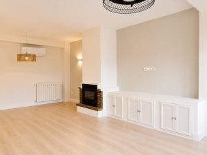 Salón con cerramiento de acero y vidrio hacia la cocina – reforma integral de vivienda en Torrelodones