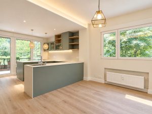 Cocina verde salvia con península blanca – reforma integral de piso en Madrid
