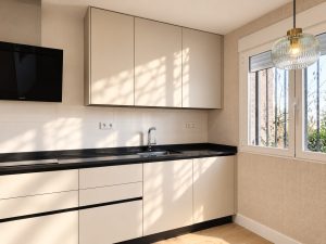 Cocina reformada con muebles blancos y encimera negra, chalet en Alcobendas