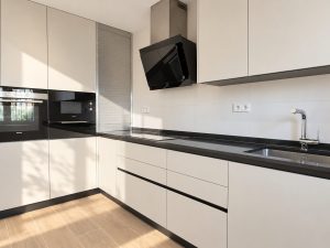 Cocina con columna de hornos integrados y campana decorativa, reforma en Alcobendas