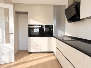 Cocina en L reformada con encimera negra y frentes blancos, Alcobendas
