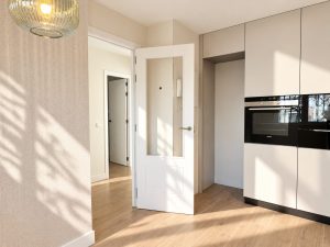 Acceso a cocina con columnas de almacenaje y horno integrado, reforma en Alcobendas