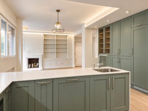 Cocina verde salvia con península blanca – reforma integral de piso en Madrid