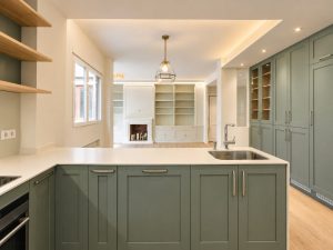 Cocina verde salvia con península blanca – reforma integral de piso en Madrid