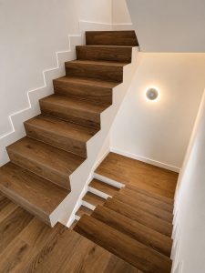 Escalera revestida en madera con aplique de luz, reforma integral en Alcobendas
