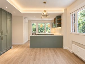 Cocina verde salvia con península blanca – reforma integral de piso en Madrid