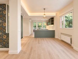 Cocina verde salvia con península blanca – reforma integral de piso en Madrid