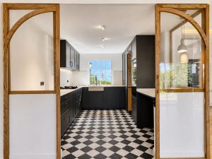Cocina azul oscuro con suelo ajedrezado y cerramiento de roble con arcos · reforma integral en Torrelodones