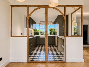 Cocina azul oscuro con suelo ajedrezado y cerramiento de roble con arcos · reforma integral en Torrelodones