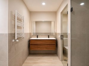 Baño principal con doble lavabo y mueble de madera – reforma integral de vivienda en Torrelodones