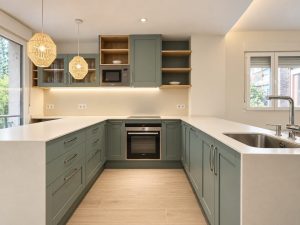Cocina verde salvia con península blanca – reforma integral de piso en Madrid