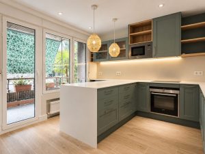 Cocina verde salvia con península blanca – reforma integral de piso en Madrid