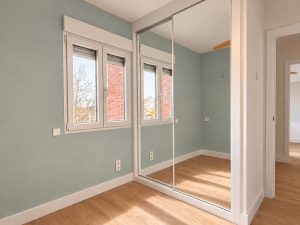 Dormitorio con armario de puertas de espejo y pared en verde suave, Alcobendas