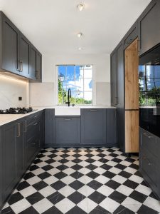Cocina azul oscuro con suelo ajedrezado y cerramiento de roble con arcos · reforma integral en Torrelodones