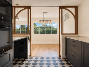 Cocina azul oscuro con suelo ajedrezado y cerramiento de roble con arcos · reforma integral en Torrelodones