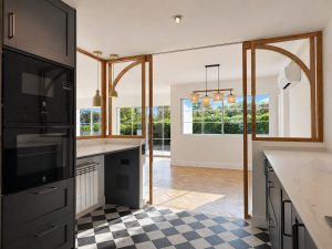 Cocina azul oscuro con suelo ajedrezado y cerramiento de roble con arcos · reforma integral en Torrelodones