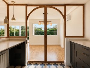 Cocina azul oscuro con suelo ajedrezado y cerramiento de roble con arcos · reforma integral en Torrelodones
